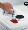 Hotpoint white gas range porcelain upswept cooktop being wiped clean around a sealed gas burner.